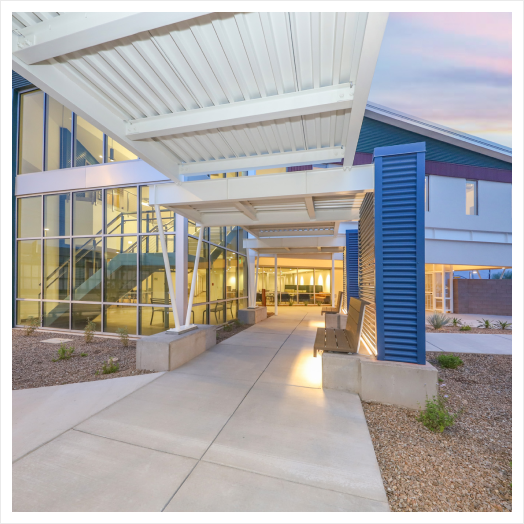 Modern building entrance with glass walls and covered walkway.